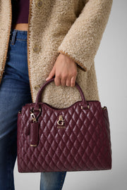 Viininpunainen Guess Tamara Satchel -käsilaukku kannettuna kädessä